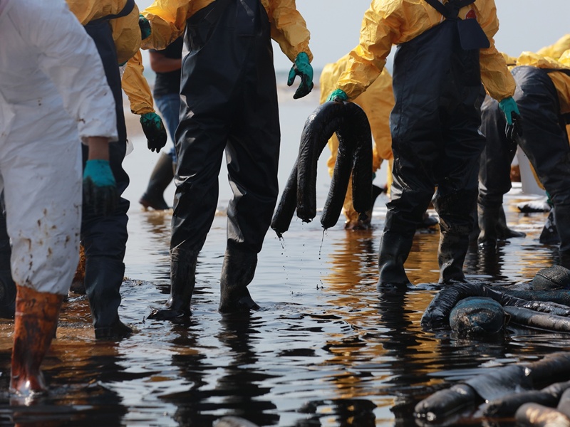 Volunteers clean the ocean coast from oil after there was a leak of crude oil from an undersea pipeline.